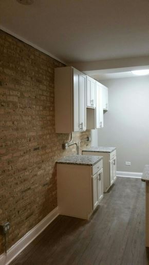 Chicago apartment for rent - a small kitchen with white cabinets and a brick wall