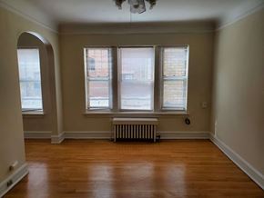 Evanston apartment for rent - a living room with wood floors and a radiator and three windows