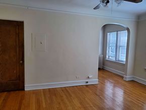 Evanston apartment for rent - a living room with white walls and wooden floors and an arched window