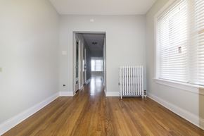 Chicago apartment for rent - a living room with wood floors and a white radiator and a hallway