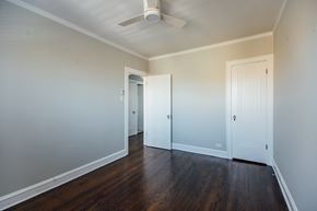 Chicago apartment for rent - a bedroom with white walls and wood floors and a ceiling fan