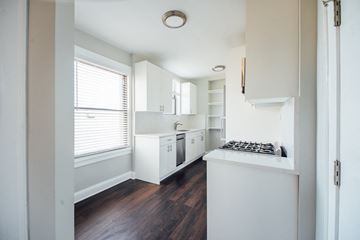 Chicago apartment for rent - a kitchen with white cabinets and a large window