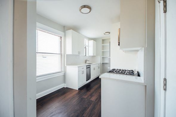 Chicago apartment for rent - a kitchen with white cabinets and a large window