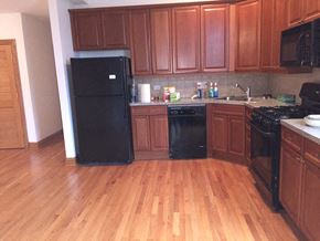 Chicago apartment for rent - a kitchen with wooden floors and black appliances