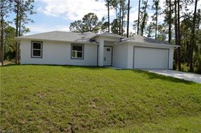 Lehigh Acres house for rent - a small white house with a lawn and trees