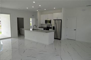 Lehigh Acres house for rent - a white kitchen with a large island and a refrigerator