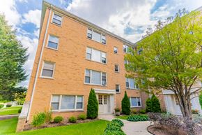 Skokie apartment for rent - exterior view of a brick apartment building with a sidewalk and grass