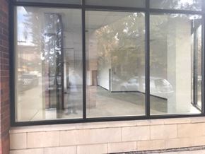 Chicago apartment for rent - A view of a street through a window with a reflection of a car and a building.