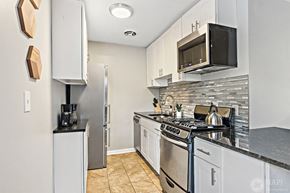 Chicago apartment for rent - a kitchen with white cabinets and a stove and a microwave