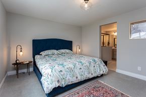 Colorado Springs house for rent - A bedroom with a large bed and a small table with a lamp.
