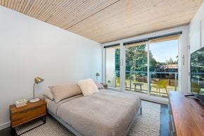 Courtenay apartment for rent - A bedroom with a bed, nightstand, and a window overlooking a backyard.