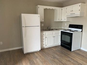 Richmond apartment for rent - A white refrigerator is in a kitchen with wooden floors.