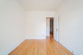 Chicago apartment for rent - a bedroom with white walls and wood floors and a door to a hallway