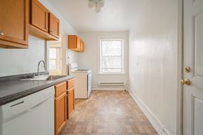 Chicago apartment for rent - a kitchen with white appliances and wooden cabinets and a window