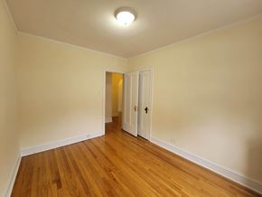 Chicago apartment for rent - a bedroom with wood floors and white walls and a door to a hallway