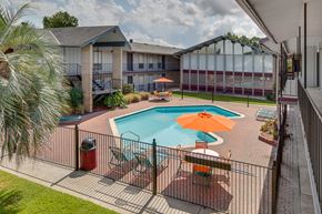 Lafayette apartment for rent - A pool with a sun lounger and umbrella in the foreground with a building in the background.