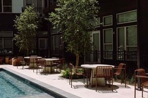 Dallas apartment for rent - a poolside seating area with tables and chairs next to a pool