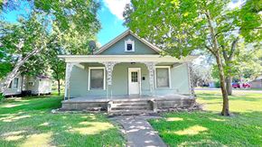 Bay City house for rent - the front of a blue house with a porch and trees