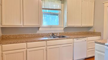 Bay City house for rent - a kitchen with white cabinets and a granite counter top