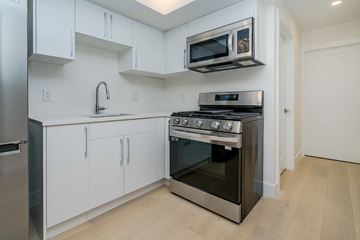 Vancouver apartment for rent - a kitchen with white cabinets and stainless steel appliances and a microwave