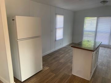 Greenwood house for rent - A white refrigerator is in a kitchen with wood floors and white cabinets.