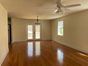 Angier house for rent - an empty living room with wooden floors and a ceiling fan
