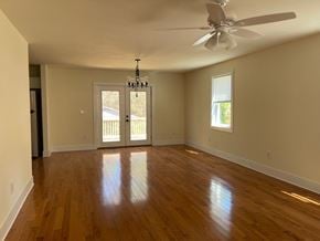 Angier house for rent - an empty living room with wooden floors and a ceiling fan