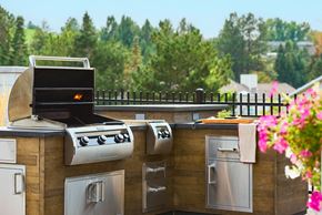 Missoula apartment for rent - A BBQ grill is on a wooden deck with a black fence and flowers in the background.