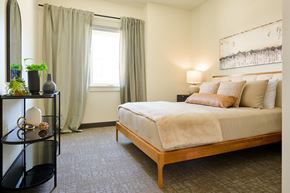 Missoula apartment for rent - A bedroom with a bed, nightstand, and a plant on a shelf.