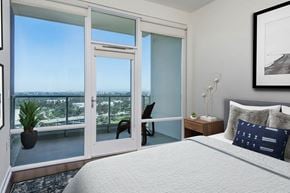 San Diego apartment for rent - A bedroom with a large bed and a view of the city through the window.