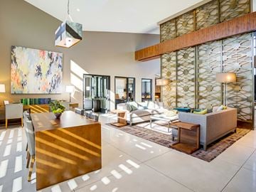 Pleasanton apartment for rent - A modern living room with a wooden table and a large abstract painting on the wall.
