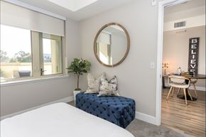 Mountain View apartment for rent - A bedroom with a round mirror and a blue bench.