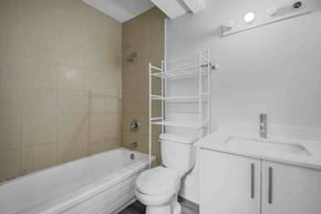Calgary apartment for rent - A white toilet sits next to a bathtub in a bathroom.