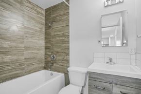 Calgary apartment for rent - A bathroom with a white tub, toilet, and sink.