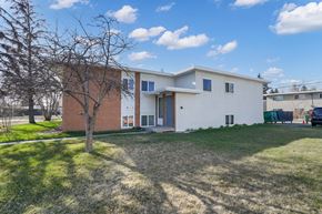 Calgary apartment for rent - A modern two-story house with a white exterior and a red brick section on the lower floor.