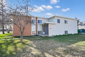 Calgary apartment for rent - A white house with a brown tree in front of it.
