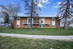 Calgary apartment for rent - A two-story apartment building with a red brick exterior and white trim.