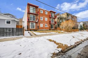 Calgary apartment for rent - A red brick apartment building with a snow-covered ground in front.