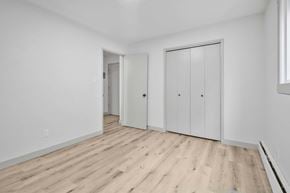 Calgary apartment for rent - A room with white walls and wooden flooring, featuring a door and a wardrobe.