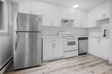 Calgary apartment for rent - A kitchen with a stainless steel refrigerator and white cabinets.