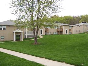 Riverside apartment for rent - A tree stands in a grassy area in front of apartment buildings.