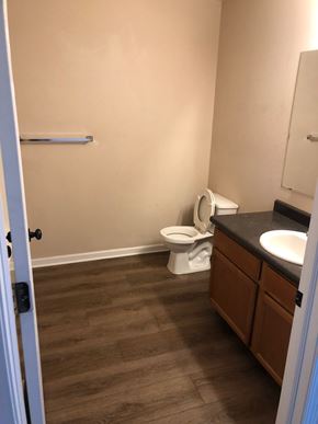 Marshall apartment for rent - A bathroom with a toilet, sink, and wooden floors.