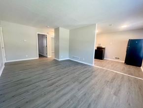 Louisville apartment for rent - an empty living room with wood flooring and a black refrigerator