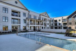 Aiken apartment for rent - A swimming pool is located in front of a building with multiple balconies.