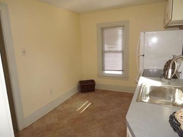 South Bend apartment for rent - A kitchen with a white fridge, sink, and a window with blinds.