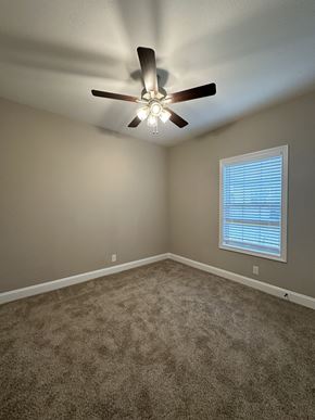 Clarksville house for rent - an empty bedroom with a ceiling fan and a window