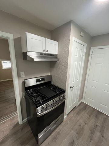 Dallas house for rent - A black stove in a kitchen with white cabinets and a white door.