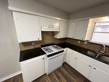 Dallas house for rent - a kitchen with white cabinets and a stove and a sink