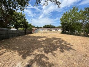 Dallas house for rent - A backyard with a fence and trees.