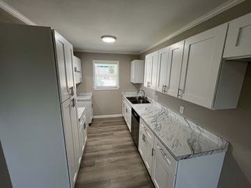 Mesquite house for rent - A kitchen with white cabinets and a marble countertop.